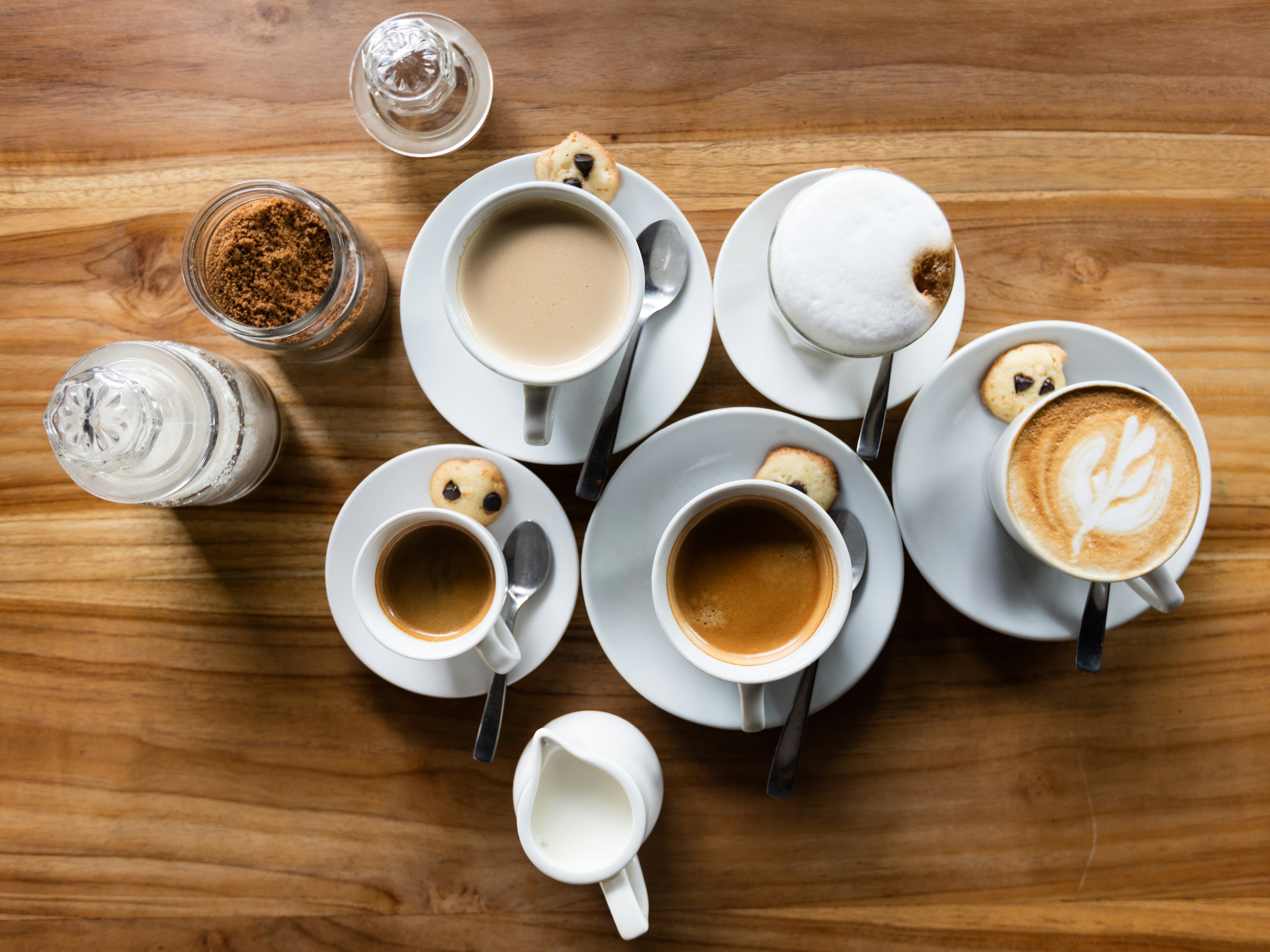 Top view of a variety of different coffees in cups on a wooden table